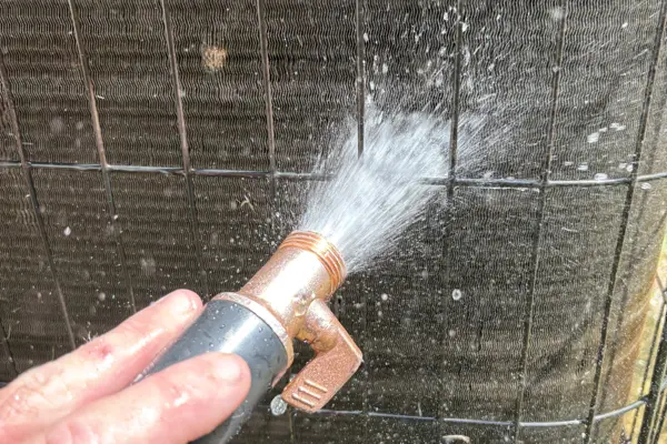 Technician rinsing a condenser coil